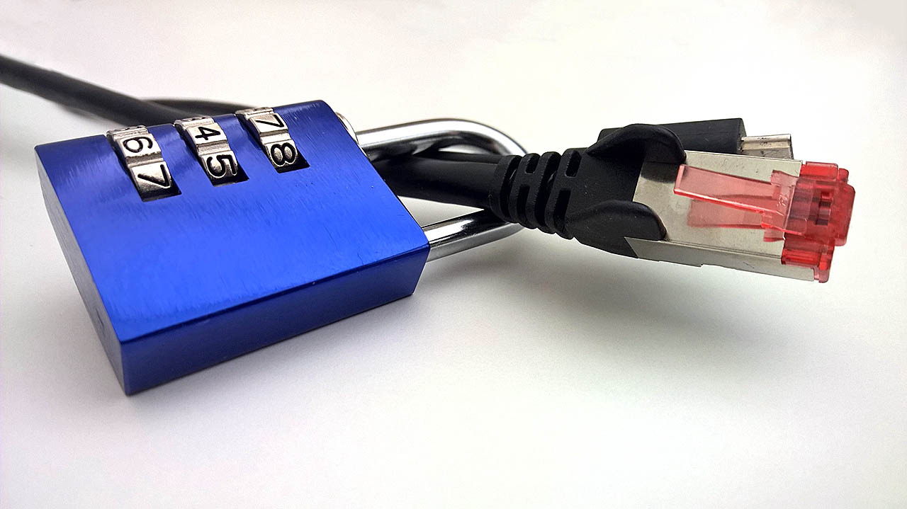 Ein LAN-Kabel mit rotem Kontakt ist durch die Schließe eines leuchtend blauen Vorhängeschlosses geführt. Das Vorhängeschloss ist abgeschlossen.